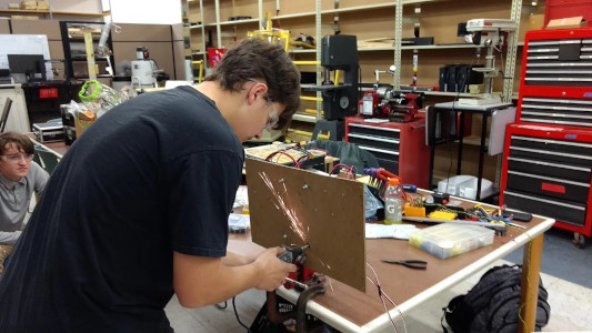 Student trimming a screw with a dremel